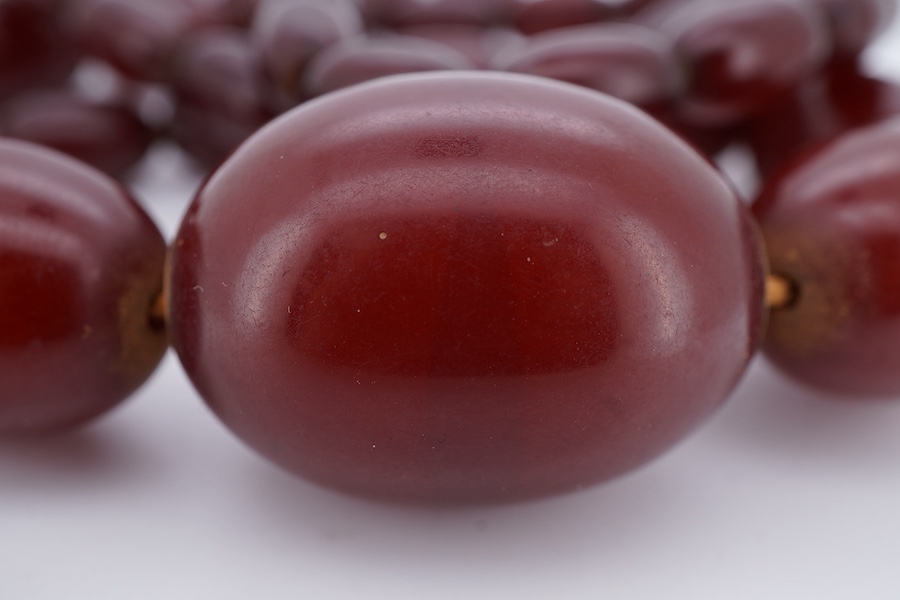 A cherry-coloured bakelite 'amber' necklace, composed of graduated oval beads measuring approximately 1.1-3cm, length 76cm, gross weight 66 grams, Condition: good, minor wear